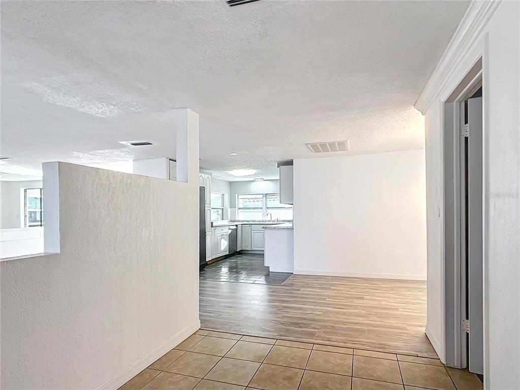 An interior view shows a tiled entryway leading to a kitchen with white cabinetry — 3640 RICHBORO DRIVE, HOLIDAY, FL