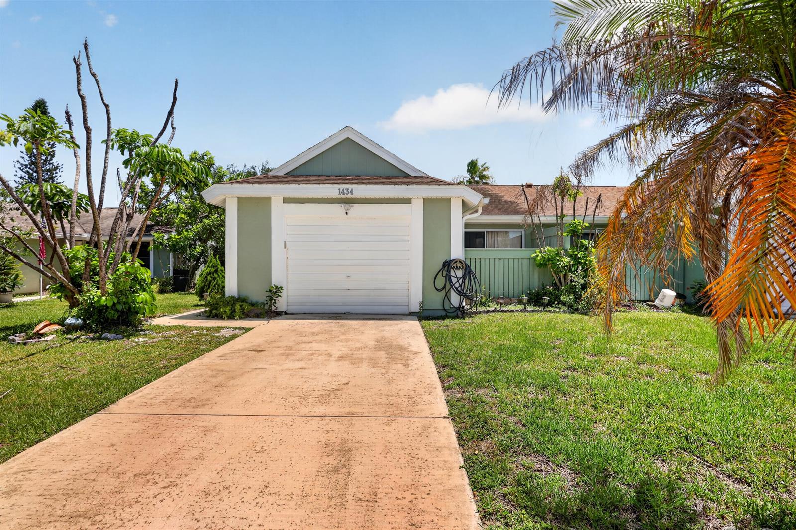 A single-story house with a white garage door, light green siding, and a concrete driveway — 1434 SE Larkwood Circle, FL 34952, FL