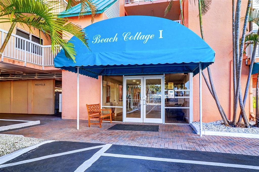 The exterior entrance of Beach Cottage I features a blue awning over glass double doors — 18400 GULF BOULEVARD UNIT 1302, INDIAN SHORES, FL