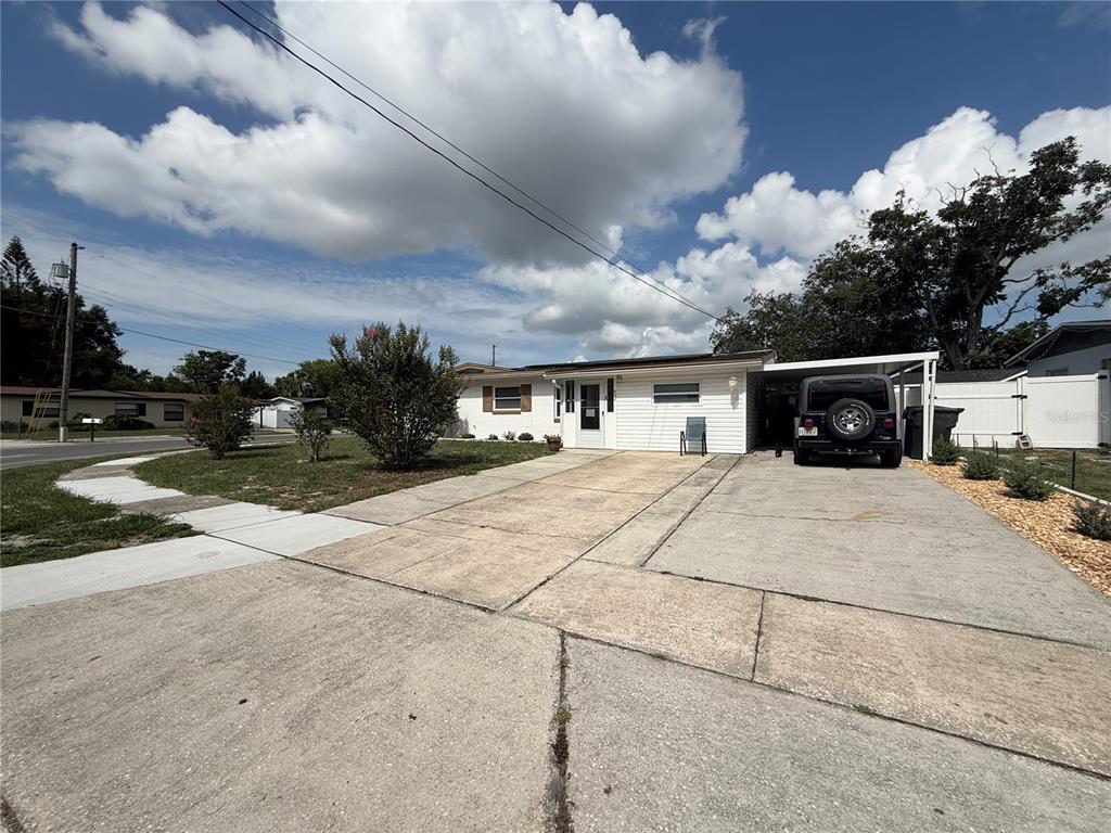 A single-story white house with a concrete driveway and a carport featuring a parked vehicle — 602 SULLIVAN AVENUE, OCOEE, FL