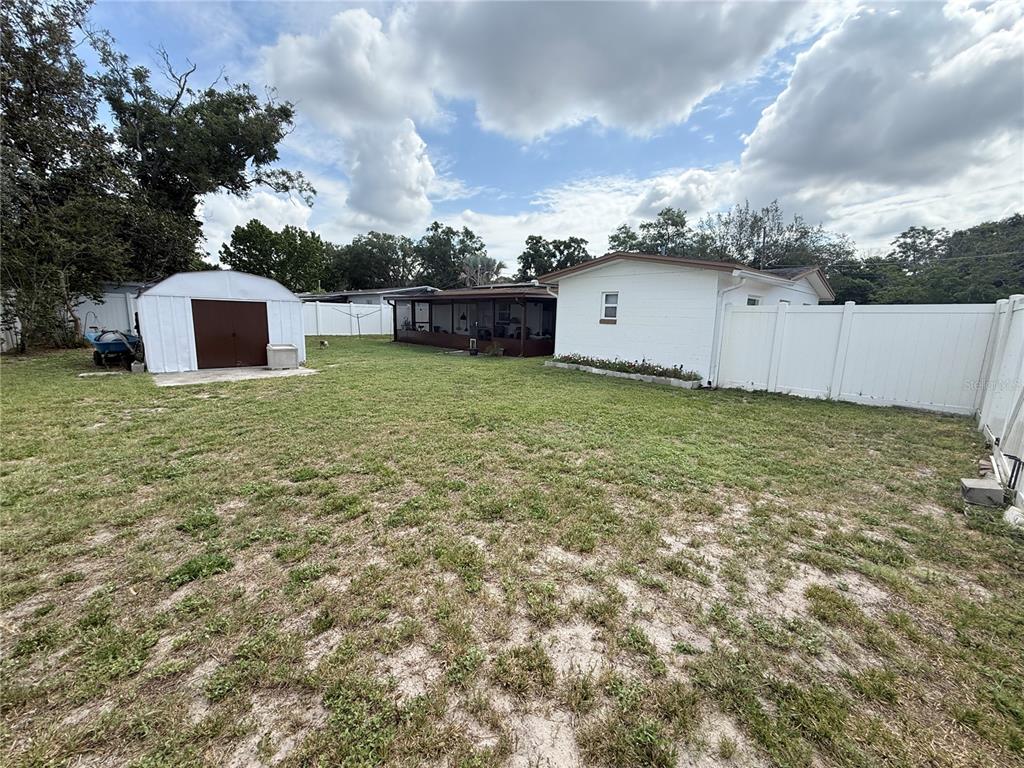 A backyard features a white house with a screened porch, a storage shed, and fencing — 602 SULLIVAN AVENUE, OCOEE, FL