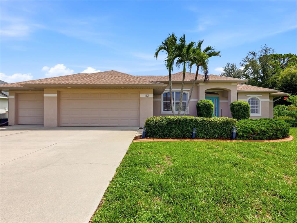 A single-story house with a beige exterior, a two-car garage, and palm trees in front — 162 MEDALIST ROAD, ROTONDA WEST, FL
