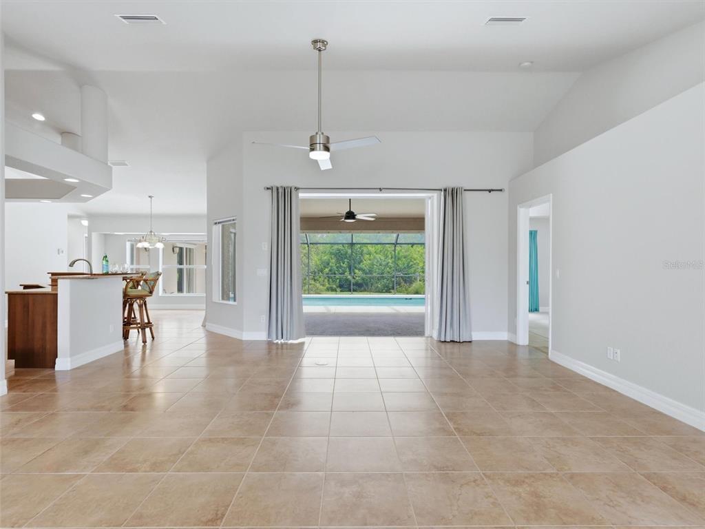 A spacious living area with tile floors opens to a screened-in pool and patio — 162 MEDALIST ROAD, ROTONDA WEST, FL