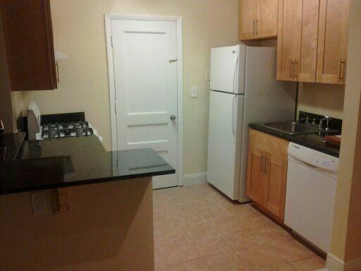 A kitchen features light wood cabinets, black countertops, a white refrigerator, and a white dishwasher — NORTH MIAMI BEACH, FL