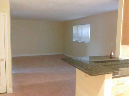 An open-concept living area features light-colored tile flooring and a granite-topped kitchen breakfast bar — NORTH MIAMI BEACH, FL