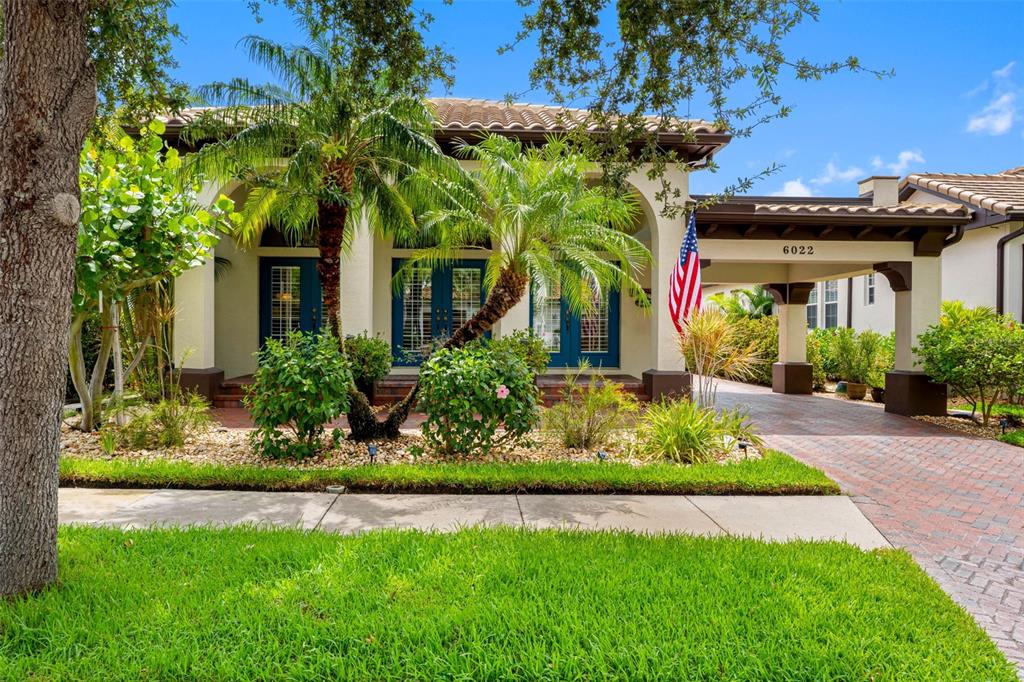 A single-story house with a brick driveway, a covered entryway, and a palm-filled front garden — 6022 BEACON SHORES STREET, TAMPA, FL