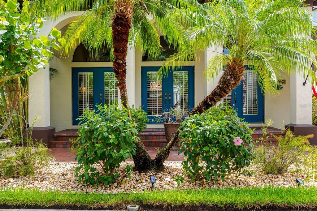 A house exterior features blue double doors, arched windows, palm trees, and a stone garden — 6022 BEACON SHORES STREET, TAMPA, FL