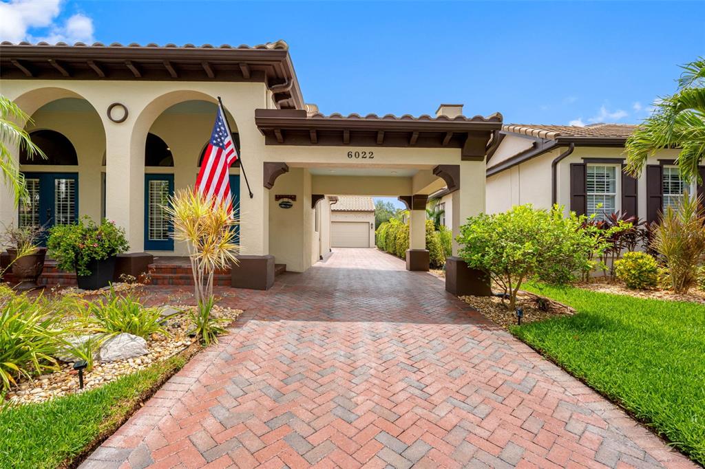 A house exterior features a brick paver driveway, a covered portico, and a tiled roof — 6022 BEACON SHORES STREET, TAMPA, FL