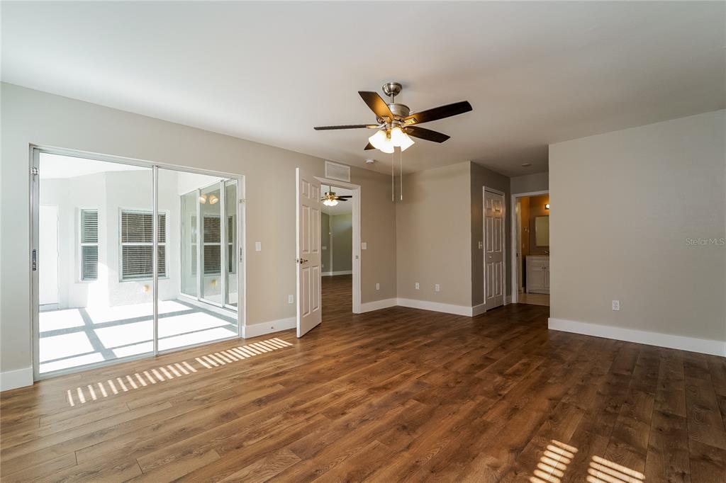 An empty room with wood-look flooring, a ceiling fan, and sliding glass doors to a patio — 1743 HAZELTON AVENUE, NORTH PORT, FL
