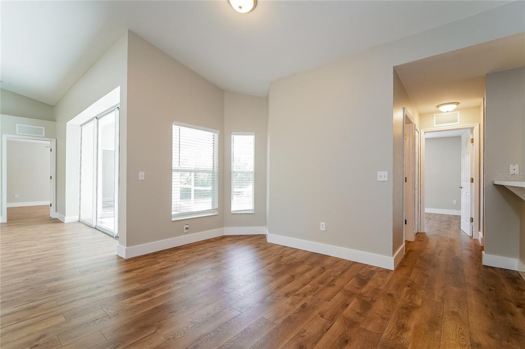 An interior view of a room with wood-look flooring, neutral walls, and a bay window — 1743 HAZELTON AVENUE, NORTH PORT, FL
