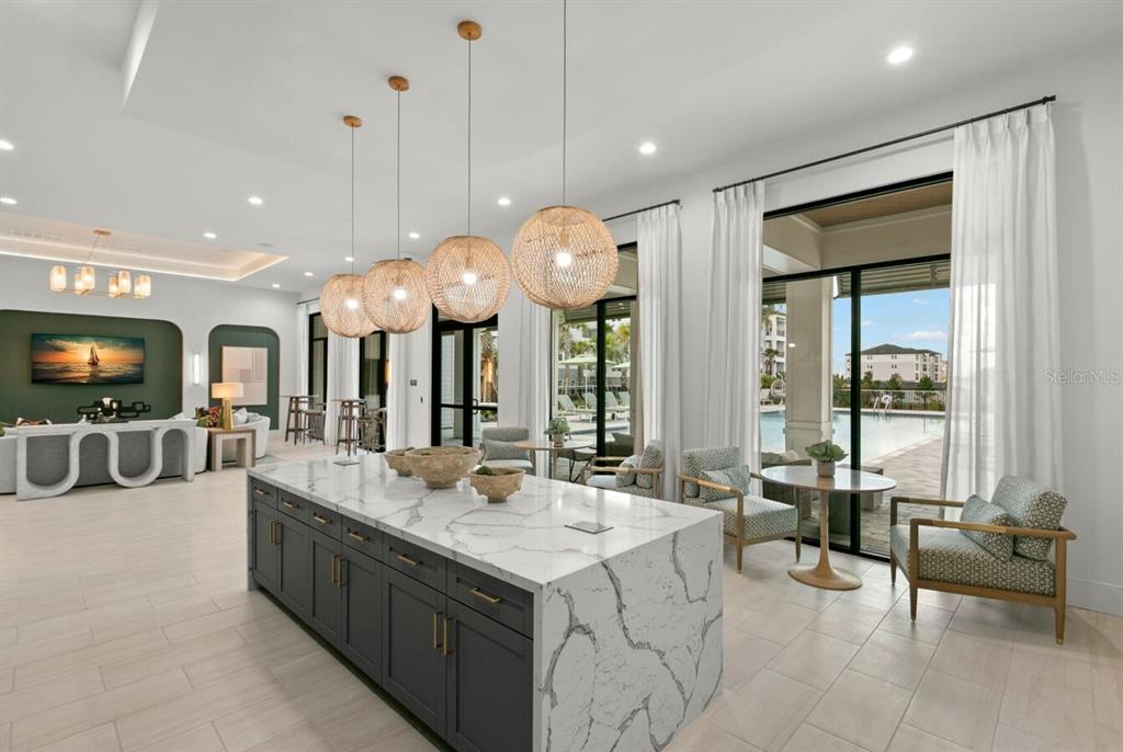 A modern kitchen island with a marble countertop sits before a room with pool views — 1310 RIDGEVIEW CIRCLE UNIT B1, DAVENPORT, FL