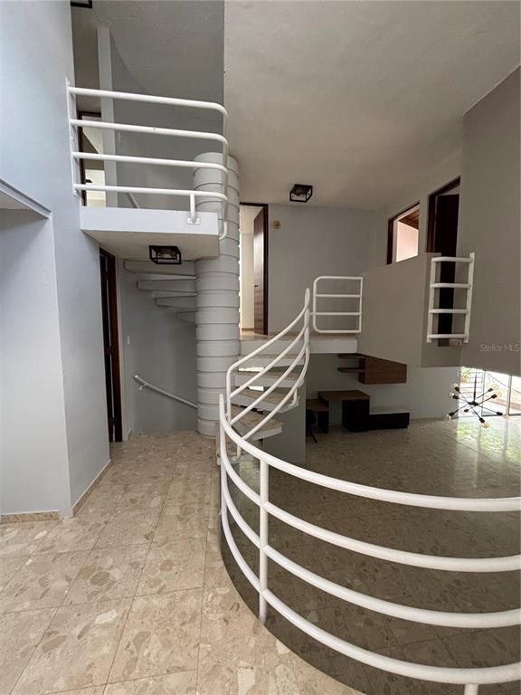 An interior view shows a spiral staircase with white railings and light-colored tile flooring — Calle 3 PASEO LAS VISTAS, SAN JUAN, PR