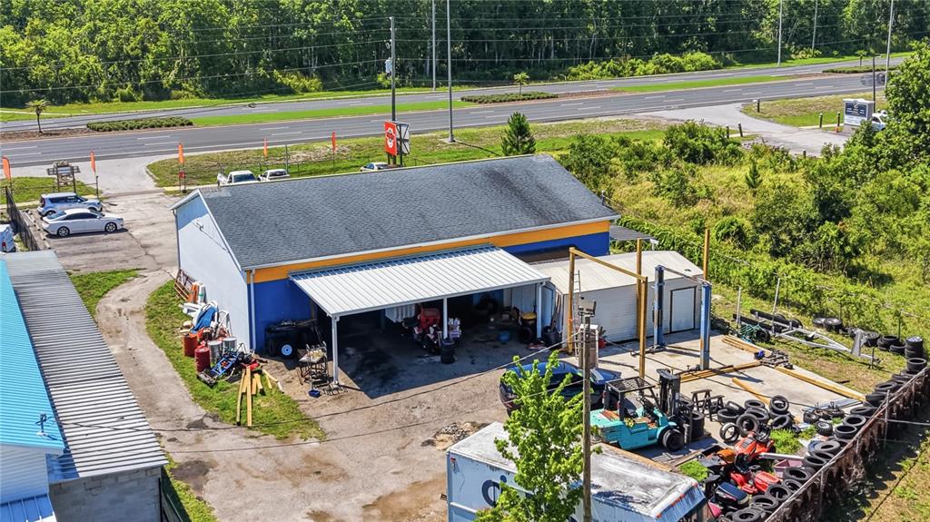 An aerial view shows a commercial building with a metal carport and an outdoor workspace — 17426 US HWY 19, HUDSON, FL