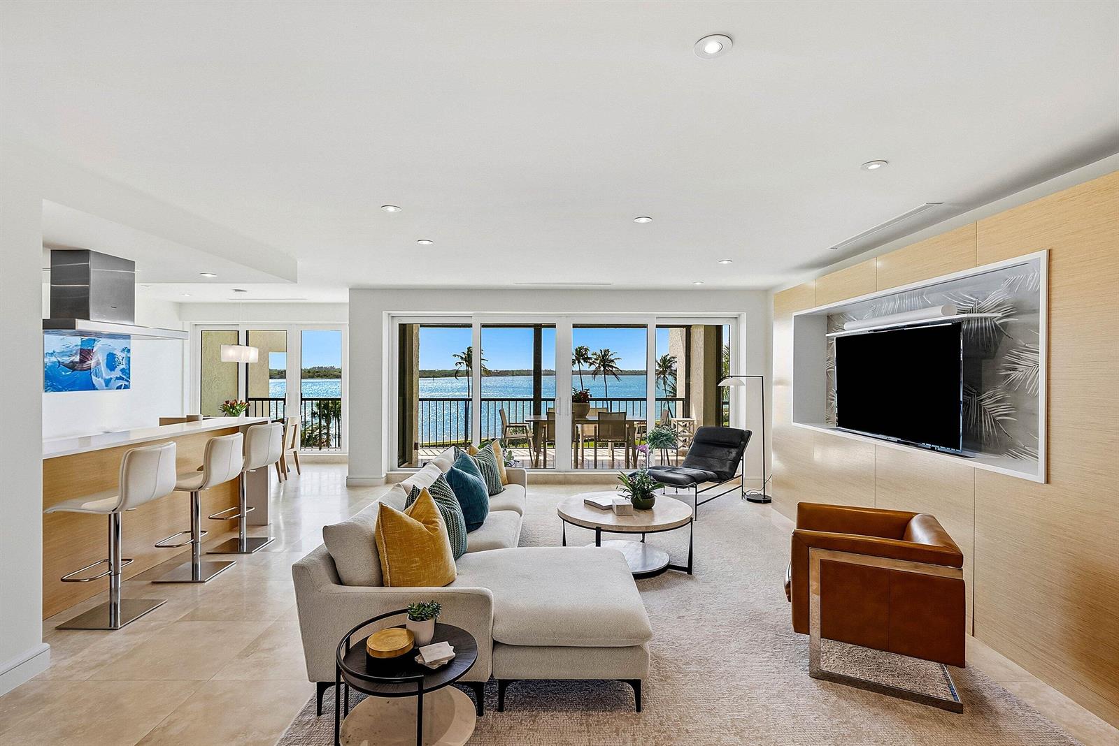 A modern living room and kitchen area features a sectional sofa, water views, and wood paneling — 2820 SE Dune Drive # 2306, Stuart FL 34996, STUART, FL