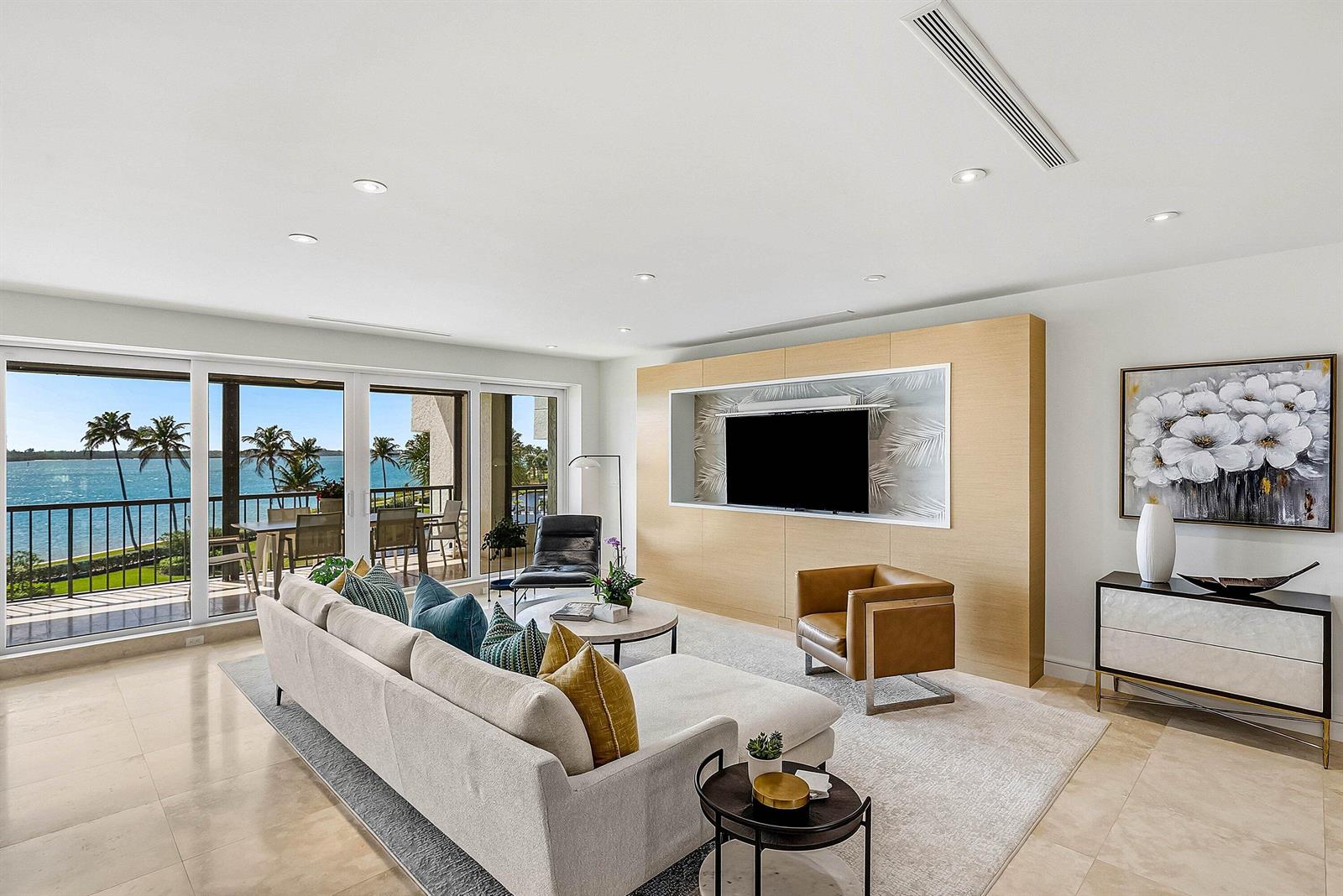 A modern living room features a large sectional sofa, wood-paneled media wall, and ocean views — 2820 SE Dune Drive # 2306, Stuart FL 34996, STUART, FL