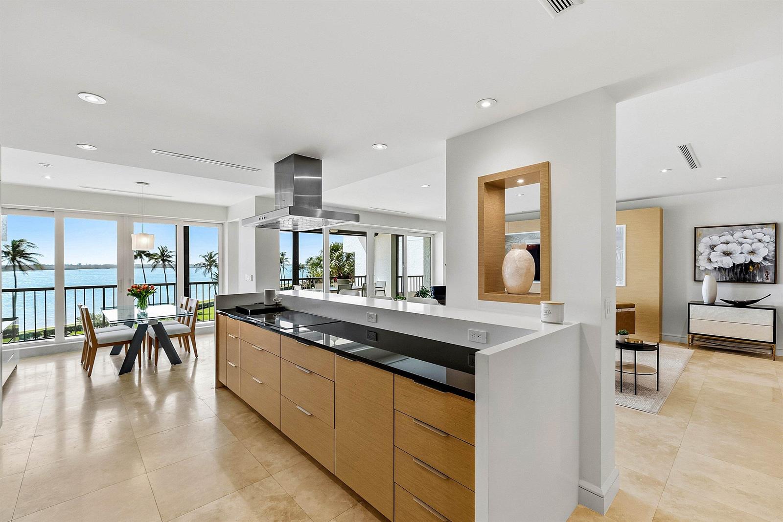 A modern kitchen with light wood cabinets and a black countertop overlooks a waterfront balcony — 2820 SE Dune Drive # 2306, Stuart FL 34996, STUART, FL