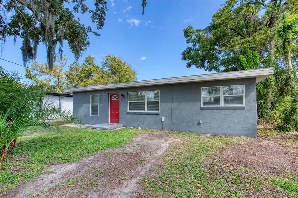 A single-story gray house with a red front door sits on a grassy lot — 843 NILES STREET, DAYTONA BEACH, FL