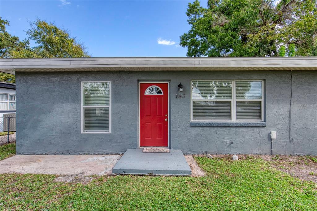 The exterior of a gray, single-story house features a red front door and two windows — 843 NILES STREET, DAYTONA BEACH, FL