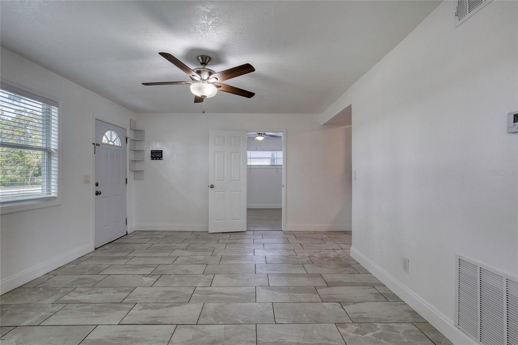A room with white walls, gray tile flooring, a ceiling fan, and an open doorway — 843 NILES STREET, DAYTONA BEACH, FL