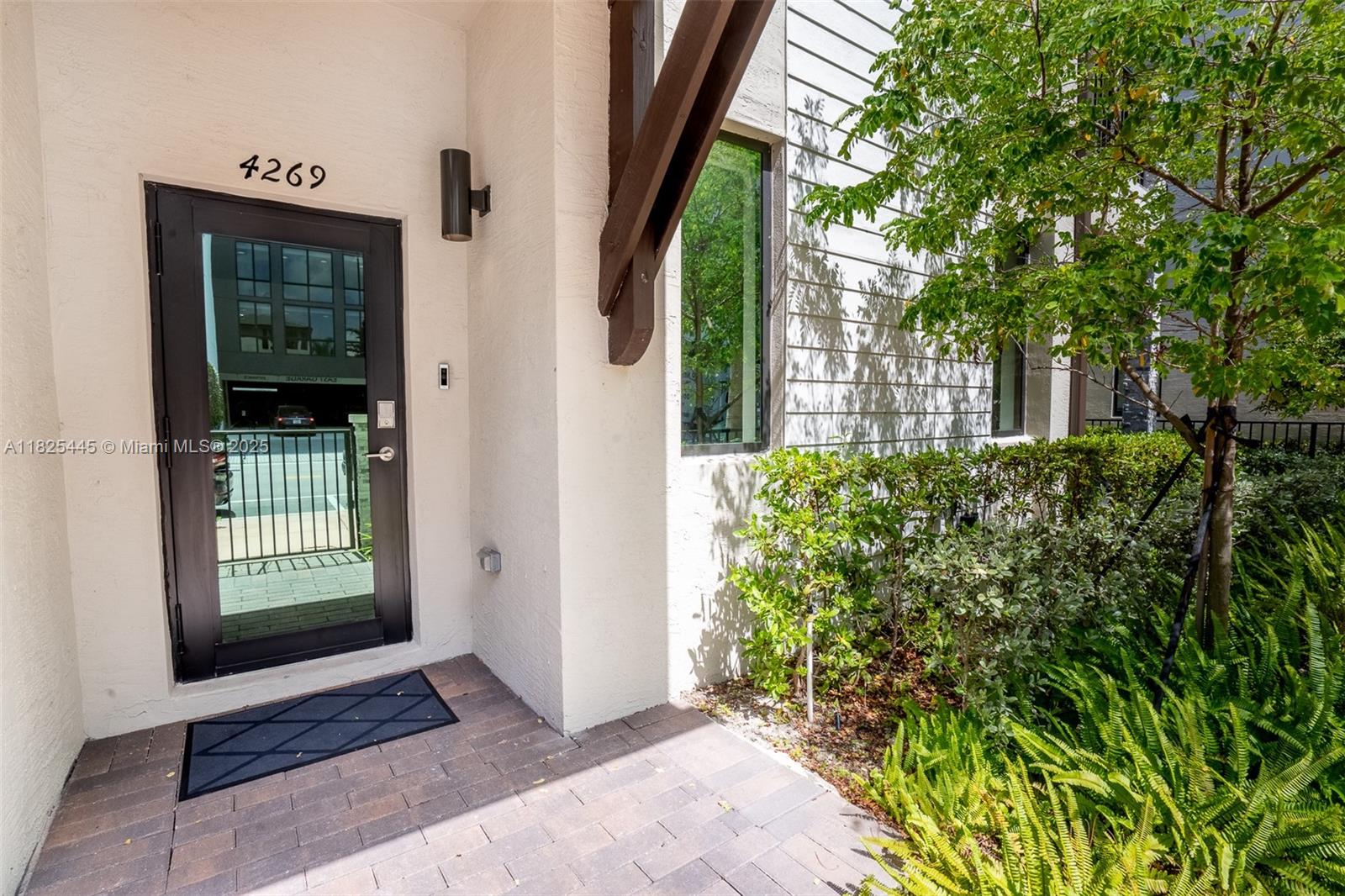 The exterior entrance features a dark-framed glass door, a brick walkway, and surrounding landscaping — 4269 NW 83rd Path, Doral FL 33166, DORAL, FL