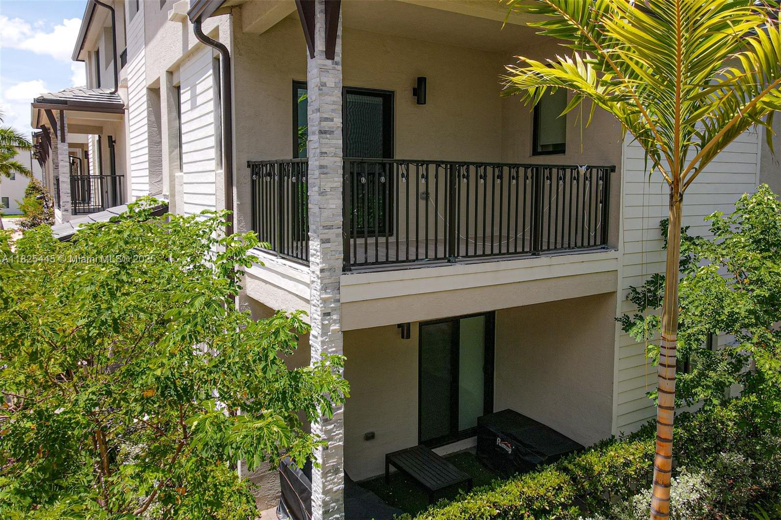 A two-story building exterior features a second-floor balcony with black railings and a ground-level patio — 4269 NW 83rd Path, Doral FL 33166, DORAL, FL