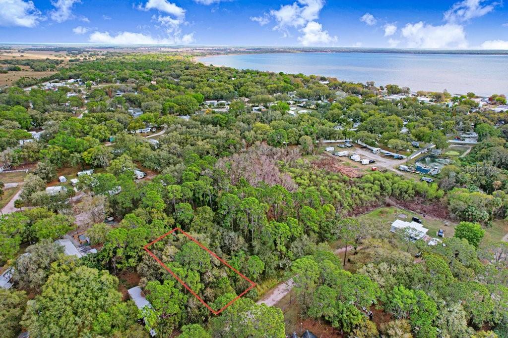 An aerial view shows a rectangular plot of land outlined in red amidst wooded surroundings — 0 YUCATAN DRIVE, LAKE WALES, FL