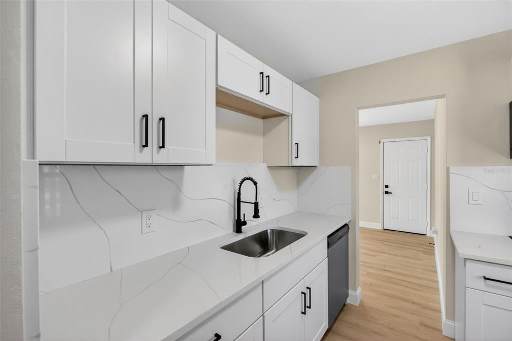 A kitchen features white cabinets, marble-look countertops, a stainless steel sink, and a dishwasher — 2597 STARLITE LANE, PORT CHARLOTTE, FL