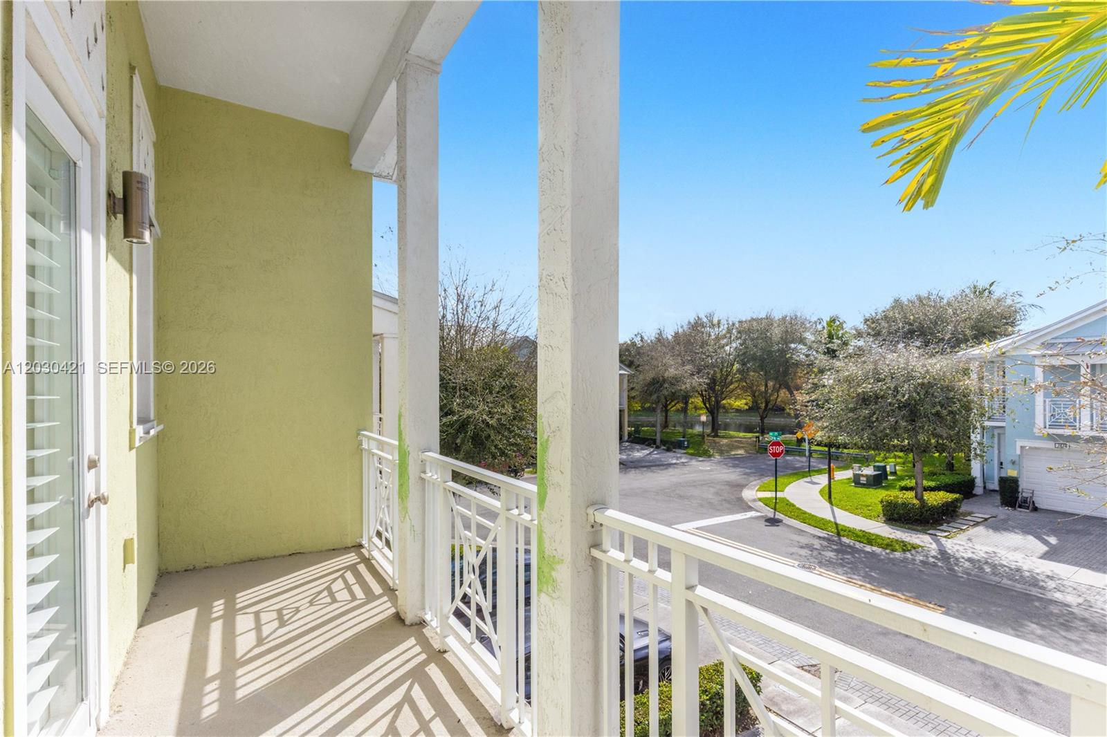 A balcony with white railings overlooks a residential street with a stop sign — 7475 NW 116th Ave, Doral FL 33178, DORAL, FL