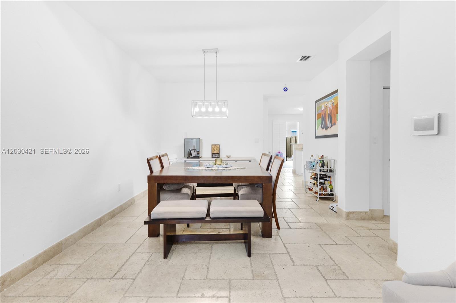 A dining room features a wooden table, a bench, chairs, and light-colored tile flooring — 7475 NW 116th Ave, Doral FL 33178, DORAL, FL