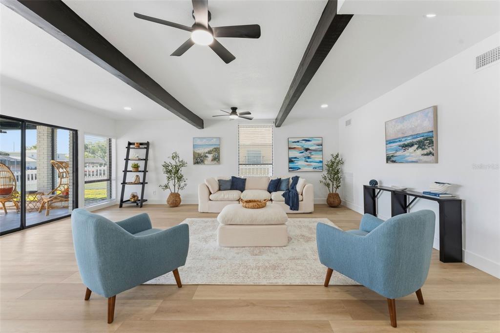 A bright living room features light wood floors, exposed ceiling beams, and two blue armchairs — 3917 E EDEN ROC CIRCLE, TAMPA, FL