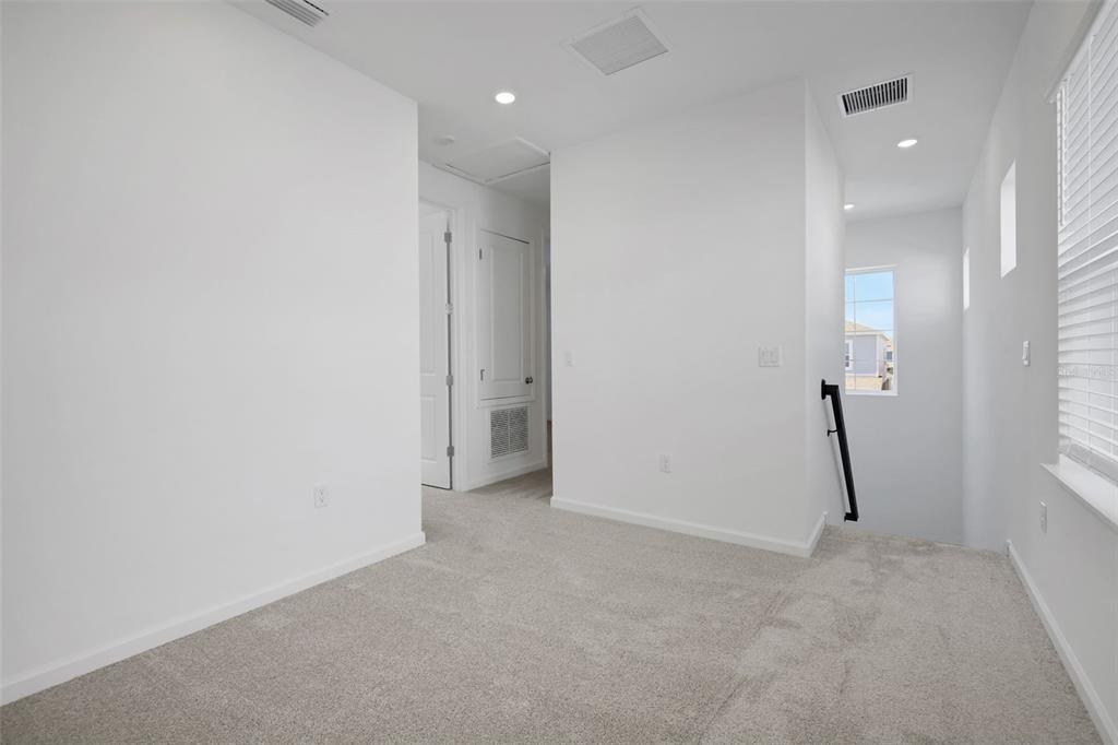 A carpeted upstairs landing features white walls, a staircase, and a window — 17125 STILLNESS ALLEY, WINTER GARDEN, FL