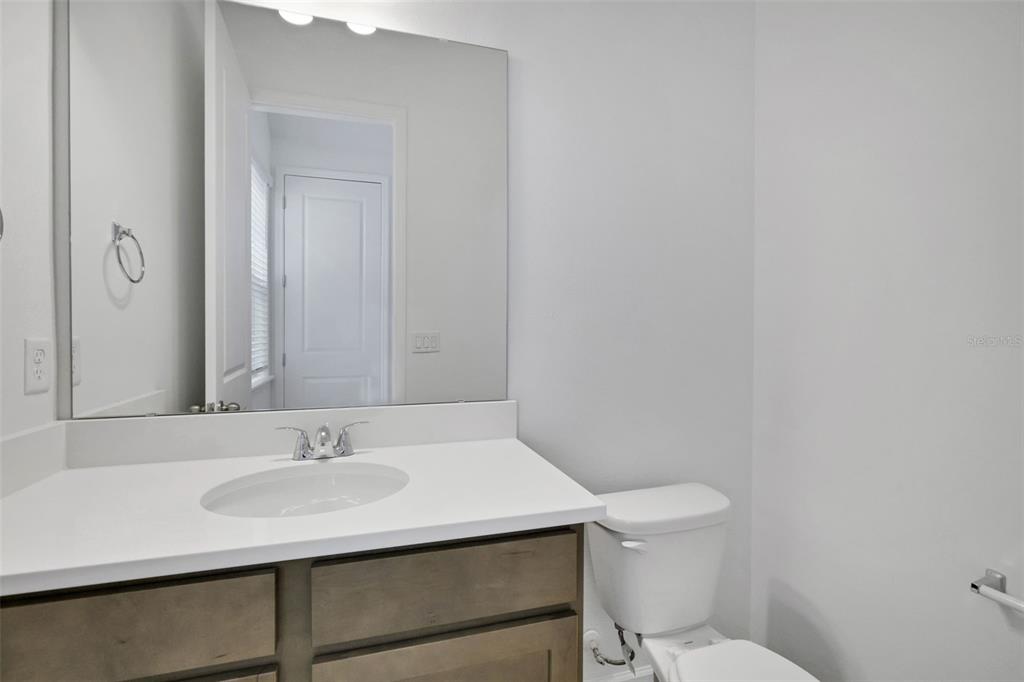 A bathroom features a vanity with a white countertop, a mirror, and a toilet — 17125 STILLNESS ALLEY, WINTER GARDEN, FL