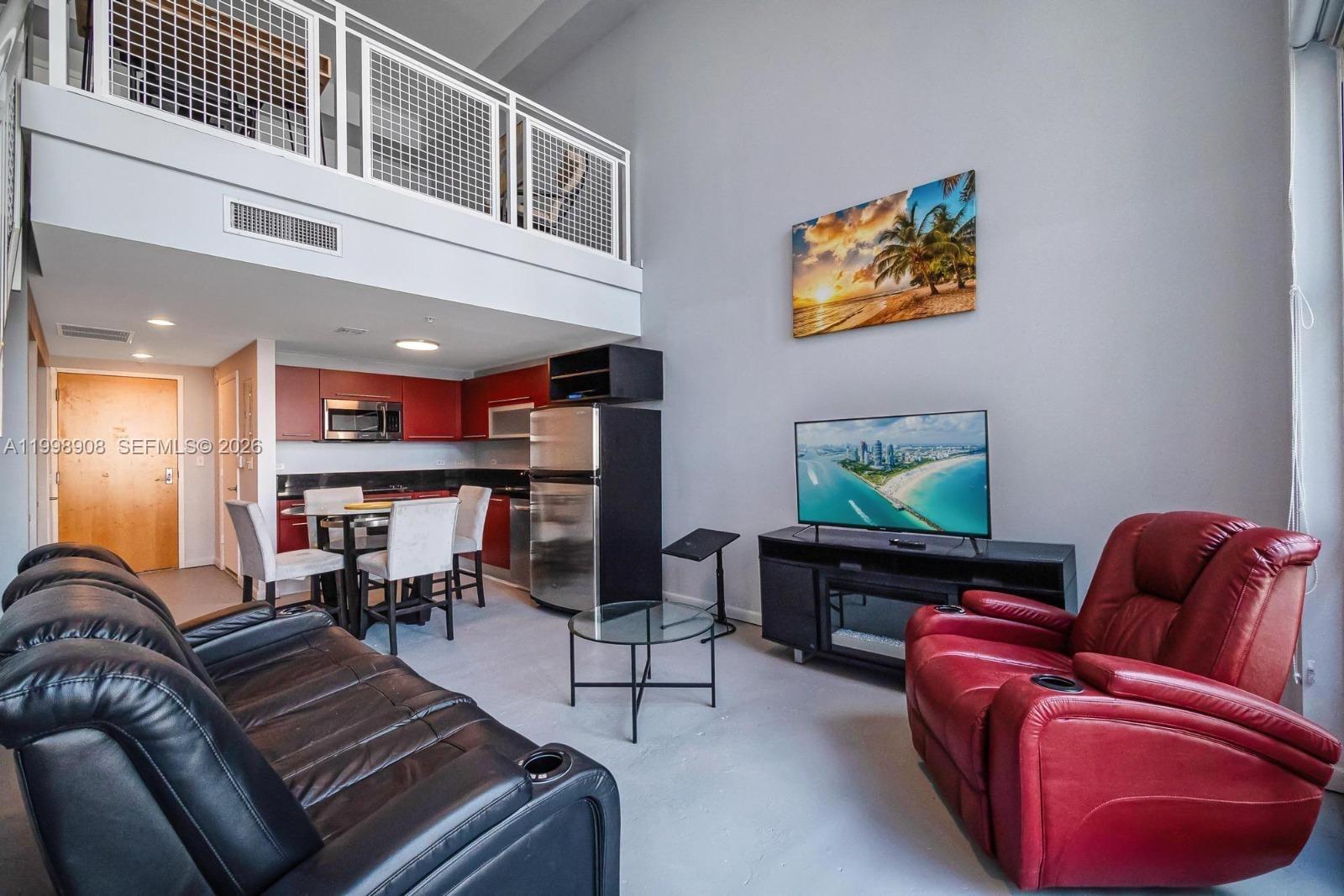 A living room with a loft area, red kitchen cabinets, and a black leather sofa — 244 Biscayne Blvd # 445, Miami FL 33132, MIAMI, FL