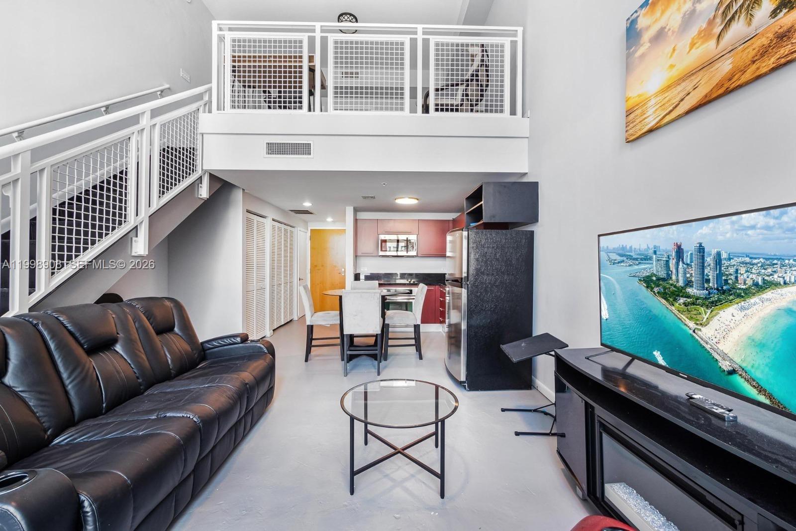 A living room with a black leather sofa, glass coffee table, and an open loft area — 244 Biscayne Blvd # 445, Miami FL 33132, MIAMI, FL