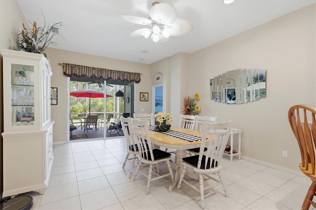 A dining room with a white table, chairs, tile floors, and a sliding glass door — 1528 SCARLETT AVENUE, NORTH PORT, FL