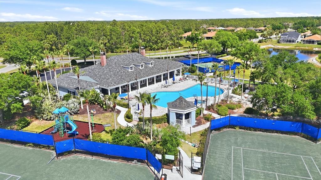An aerial view shows a community clubhouse with a swimming pool, playground, and tennis courts — 1528 SCARLETT AVENUE, NORTH PORT, FL