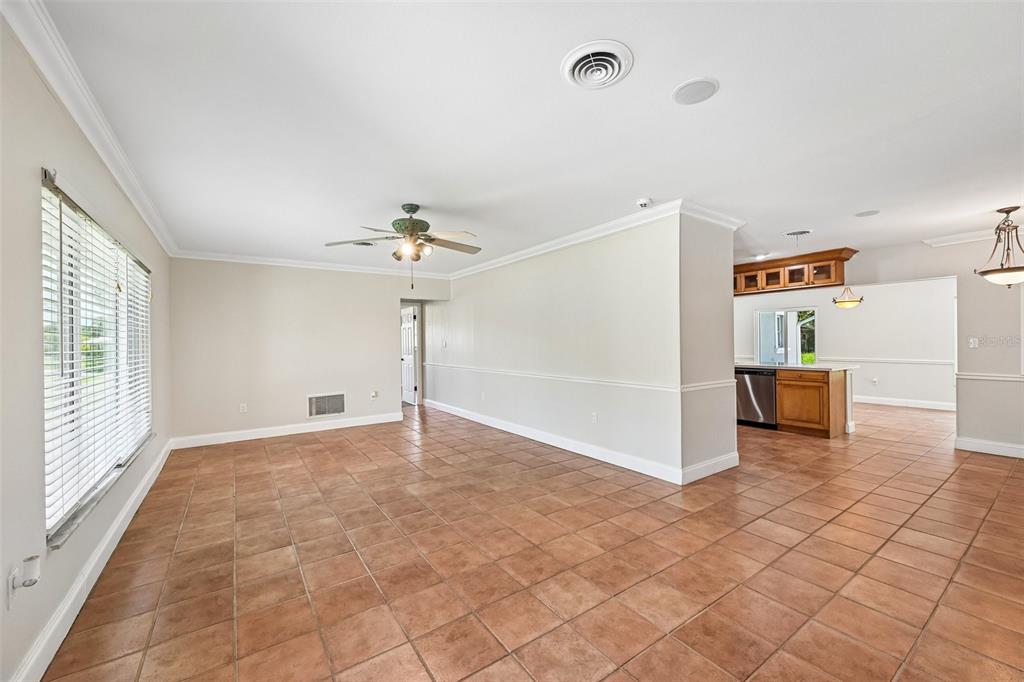A spacious living room with tile flooring, a ceiling fan, and an open kitchen beyond — 209 PALM AVENUE, NOKOMIS, FL
