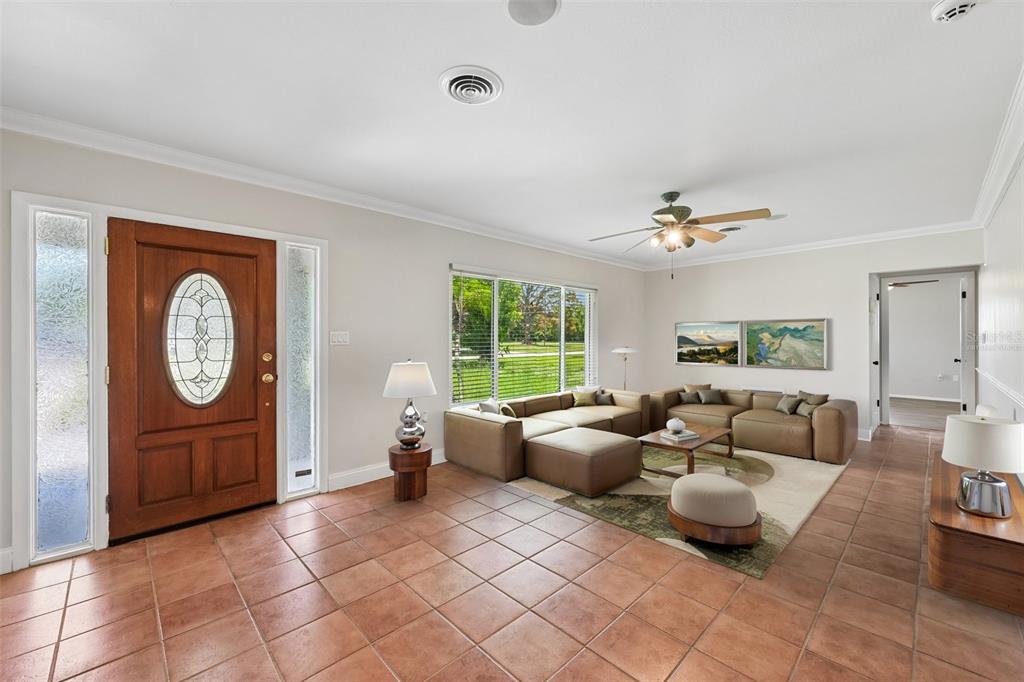A living room with tile flooring, a wooden front door, and a tan sectional sofa — 209 PALM AVENUE, NOKOMIS, FL