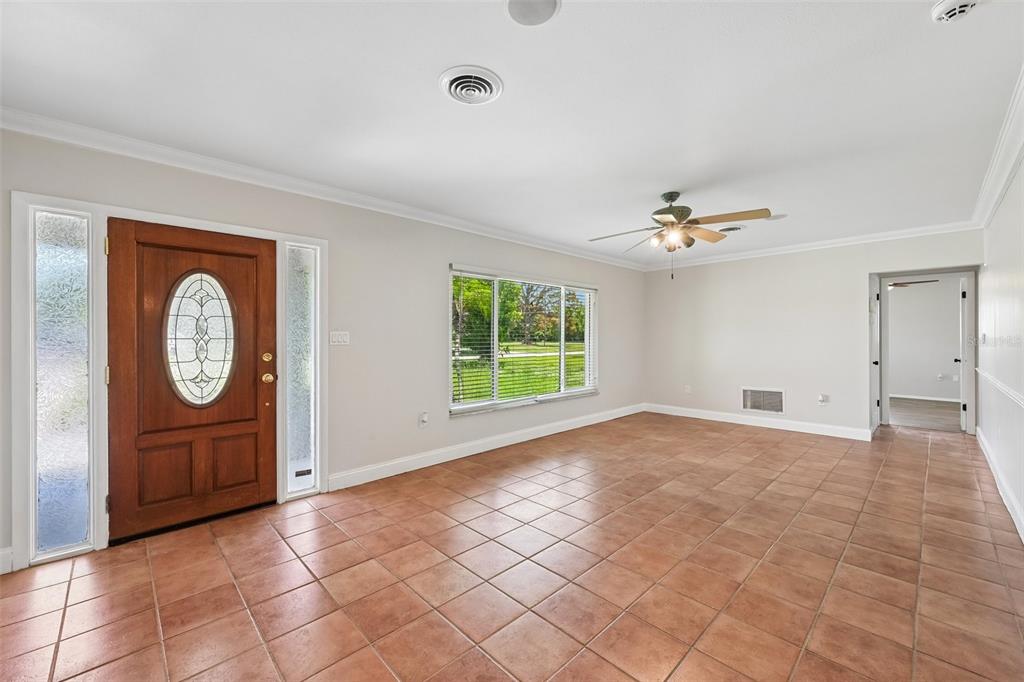 A living room with light walls, tile flooring, a ceiling fan, and a wooden front door — 209 PALM AVENUE, NOKOMIS, FL