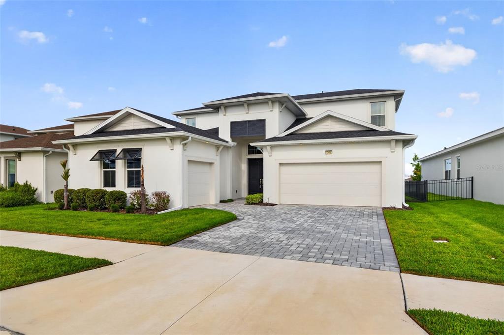 A two-story white house with a paved driveway, a three-car garage, and a green lawn — 8346 IVY STARK BOULEVARD, WESLEY CHAPEL, FL