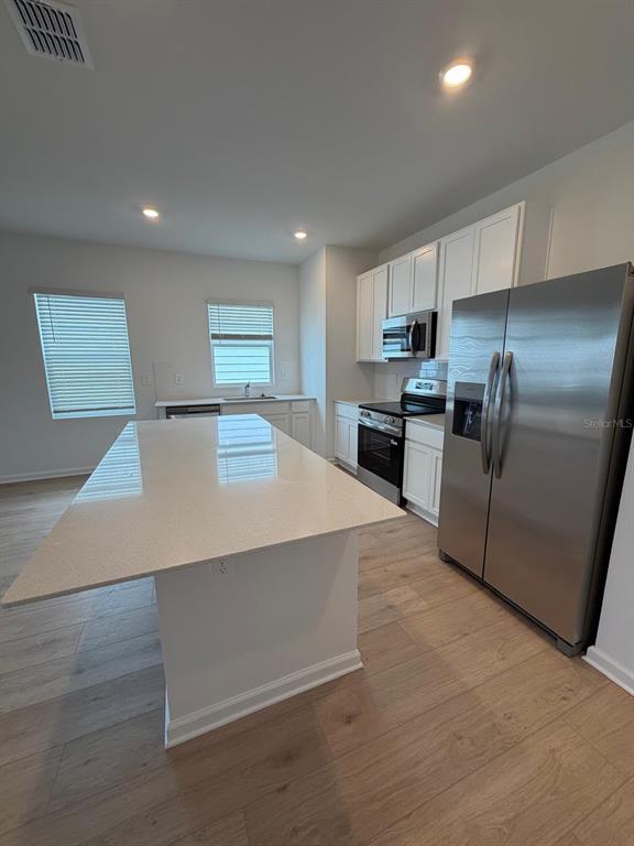 A modern kitchen features white cabinetry, stainless steel appliances, and a large quartz island — 5175 LOYALTY DRIVE, ST CLOUD, FL