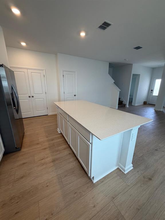 A kitchen island with a light-colored countertop sits on wood-look flooring in an open-concept room — 5175 LOYALTY DRIVE, ST CLOUD, FL