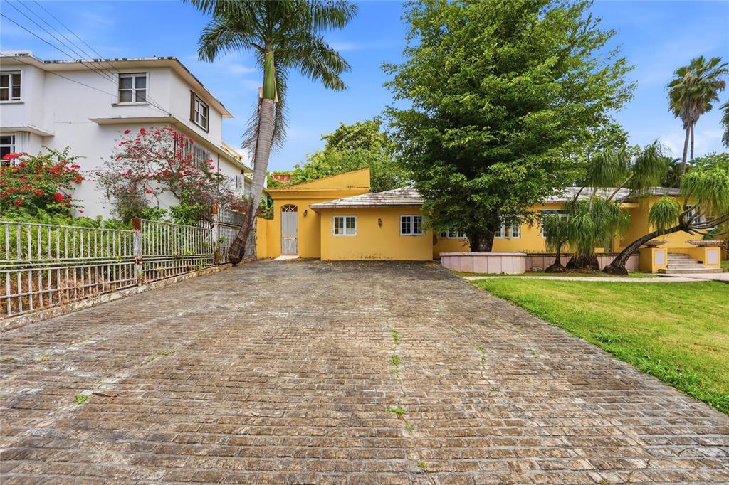 A yellow house with a brick driveway and a large tree in the front yard — 2 CALLE J, GUAYNABO, PR