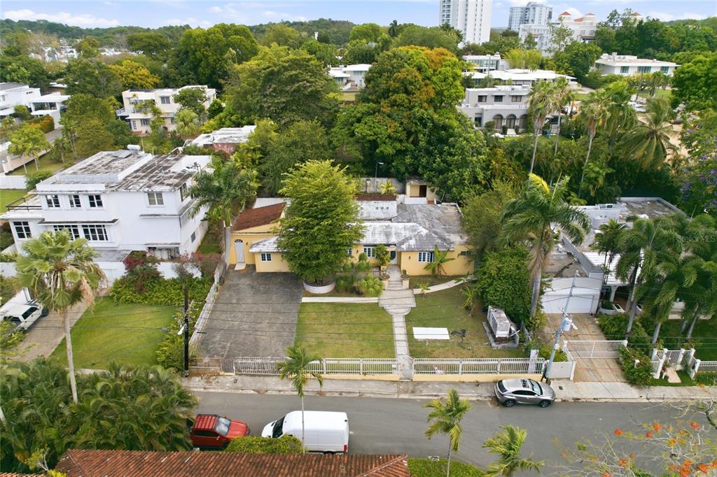 An aerial view shows a yellow single-story house with a driveway and surrounding tropical landscaping — 2 CALLE J, GUAYNABO, PR