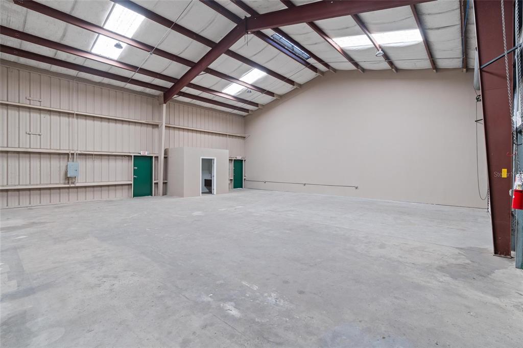 An empty warehouse space features a concrete floor, metal walls, and exposed ceiling beams — 743 WESLEY AVENUE, TARPON SPRINGS, FL