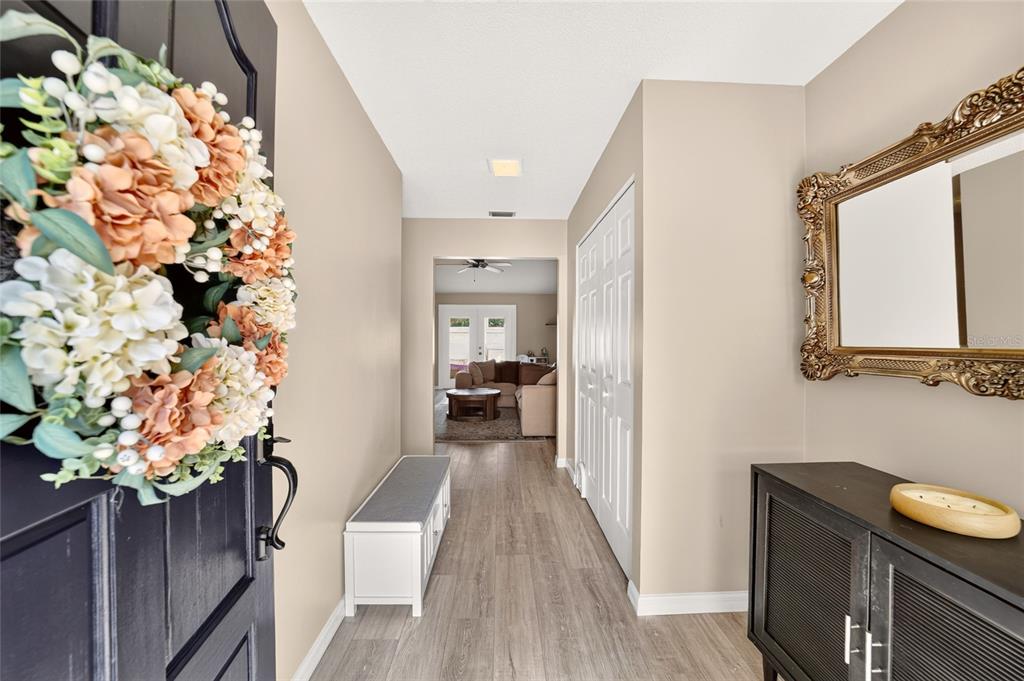 An entryway with a floral wreath on the door, a bench, and a wall mirror — 1904 SE 37TH COURT CIRCLE, OCALA, FL