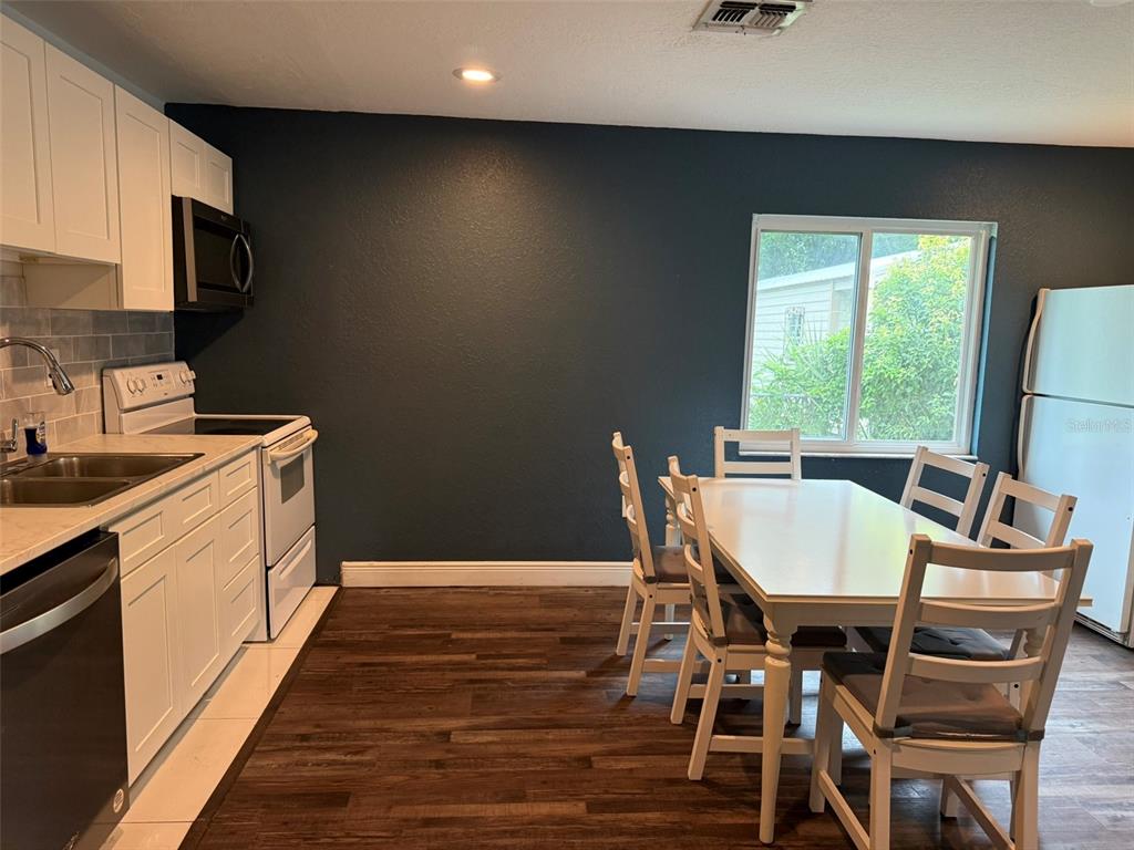 A kitchen features white cabinets, dark blue walls, a dining table, and wood-look flooring — 20785 W MCKINNEY AVENUE, DUNNELLON, FL