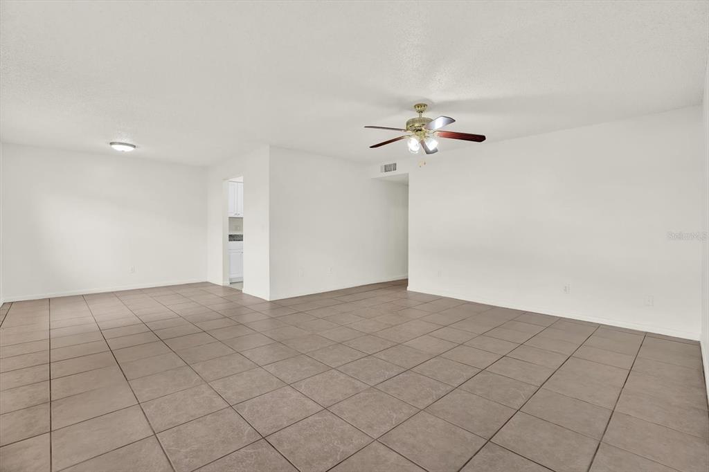 An empty room features white walls, a ceiling fan, and large square floor tiles — 9130 TUDOR DRIVE UNIT M105, TAMPA, FL