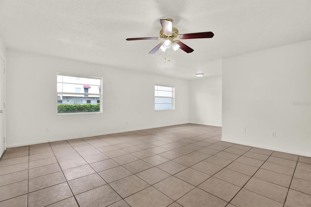 An empty room features white walls, a ceiling fan, and light-colored tile flooring — 9130 TUDOR DRIVE UNIT M105, TAMPA, FL