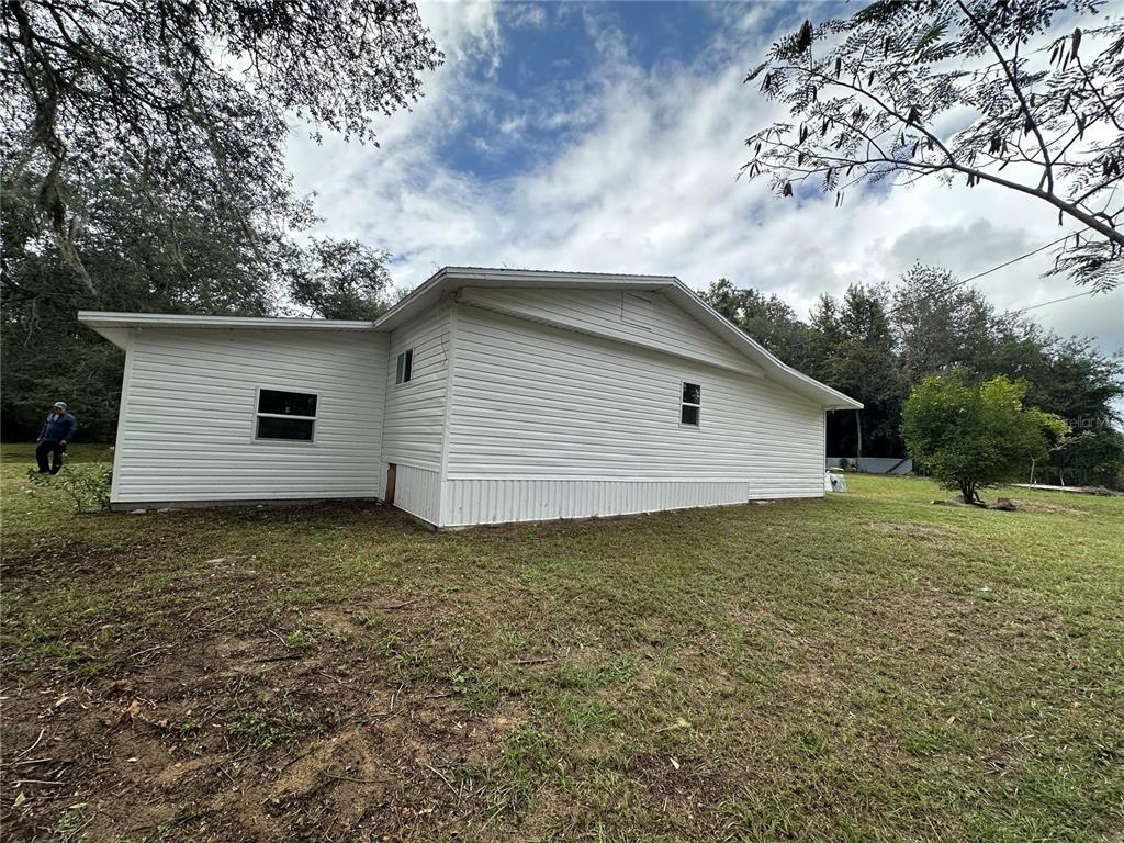 The exterior of a white, single-story house with vinyl siding sits on a grassy lot — 17405 NE 38TH LANE ROAD, SILVER SPRINGS, FL